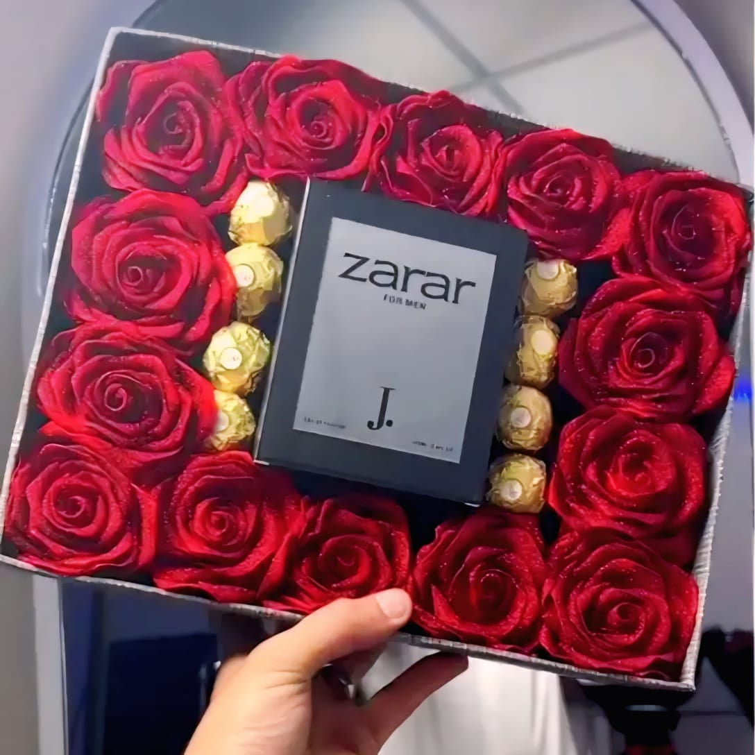 Box of red roses with a Ferrero Rocher chocolate and a 'zarrar' product inside, held by a hand.