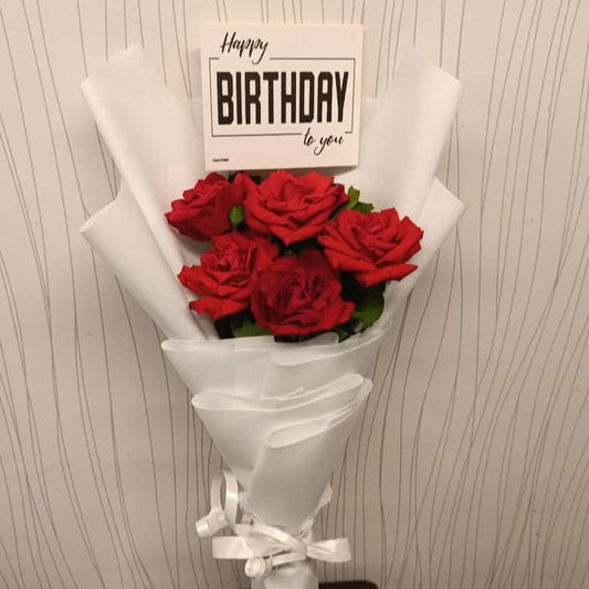 Bouquet of red roses with a 'Happy Birthday' card on a textured wall background