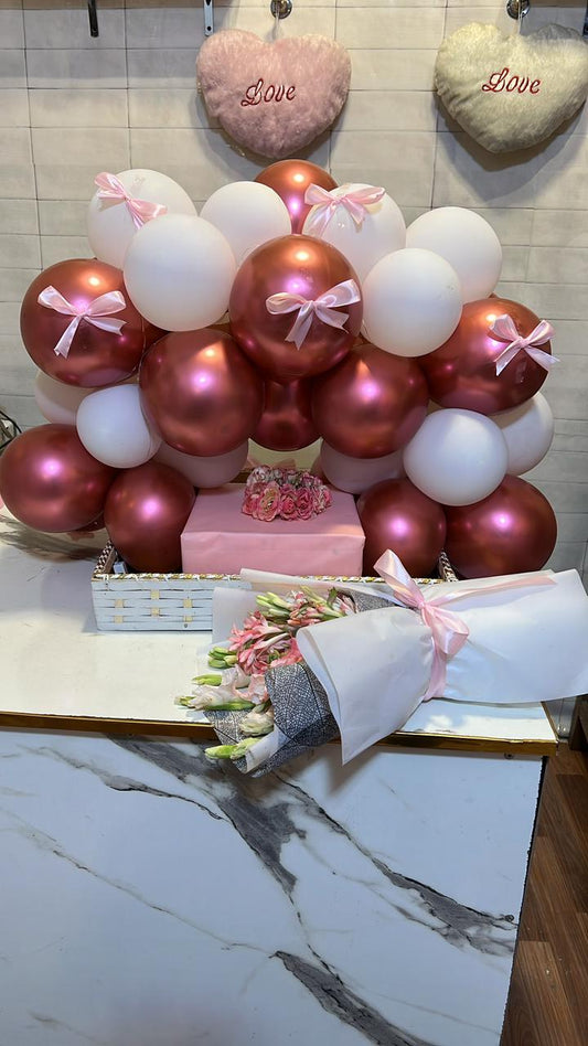 a decorative arrangement of a bunch of balloons, a cake wrapped in gift box and a flower bouquet