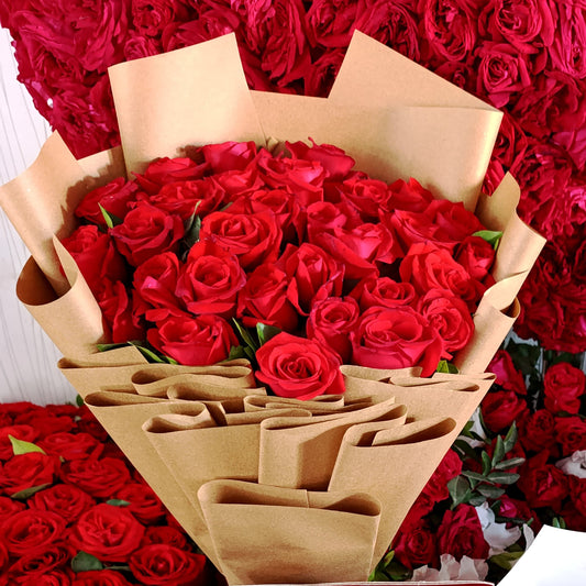 Bouquet of red roses and a cake with 'You Complete Me' text in front of more red roses.