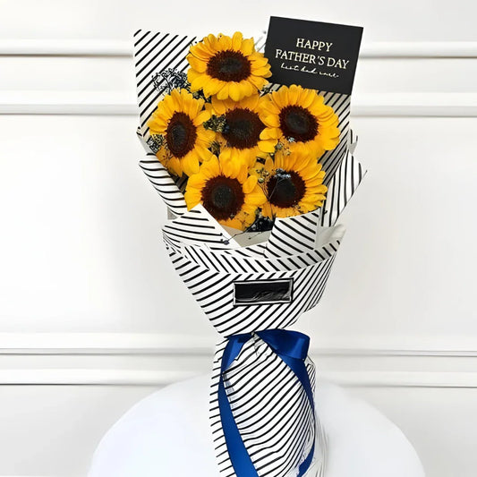 Soft Whisper Bouquet featuring six fresh sunflowers wrapped in black and white striped paper with a blue ribbon by Flower House