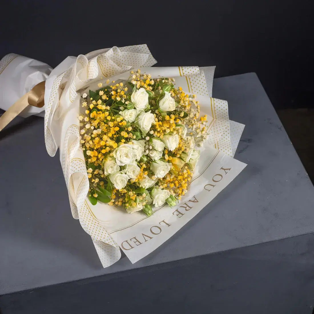 Golden Harmony bouquet wrapped in white paper with tan ribbon